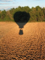my shadow flying over a cut field at the beginning of the fall season